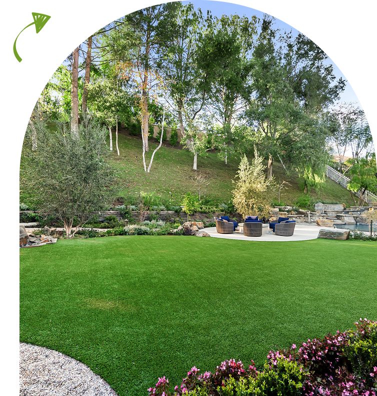 Outdoor area with a lush green lawn, a circular seating patio, and surrounding trees and plants under a clear sky.